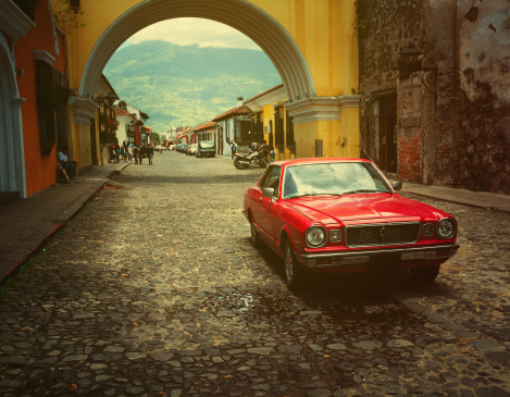 vintage red car in antigua guatemala, driving on the famous street of the Arch.