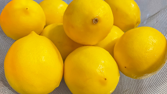 ripe yellow lemons in a metal strainer. close up