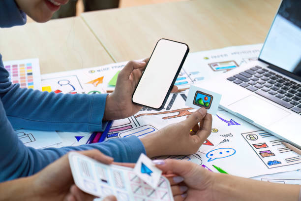 istock Blank screen mockup of man hand working on smartphone work while sitting at the table, mockup blank screen for brainstorming about mobile app interface wireframe design on desk at modern office 1740082018
