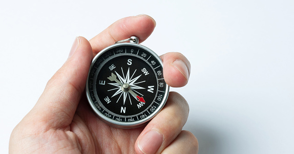 Hand holding a compass against white background