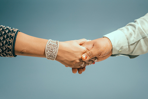 Multiracial couple holding hands together in love. Conceptual image of world unity interracial love and understanding in tolerance and diversity.