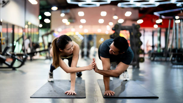 athletic sportsman and sportswoman doing push ups together at fitness gym: strength, unity, and motivation - flexing muscles fotos imagens e fotografias de stock