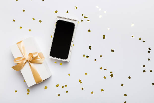 istock Opened gift box with gold ribbon and smartphone on color background, top view. Blank open box packaging mockup , Template for your design - branding mockup 1740228986