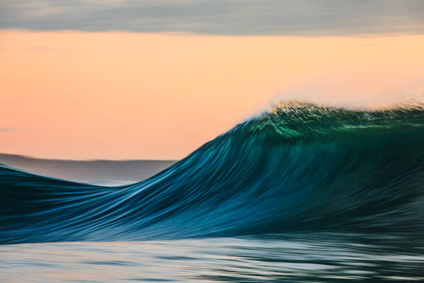 istock Smooth curved waves in the ocean with golden sky at dusk with slow shutter 1740248942