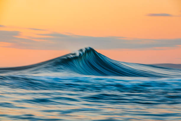 istock Smooth curved waves in the ocean with golden sky at dusk with slow shutter 1740248956