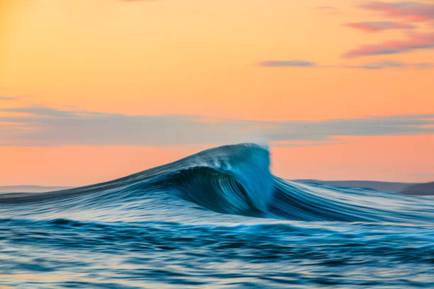 istock Smooth curved waves in the ocean with golden sky at dusk with slow shutter 1740248964