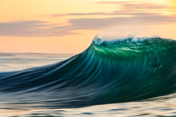 istock Smooth curved waves in the ocean with golden sky at dusk with slow shutter 1740249520