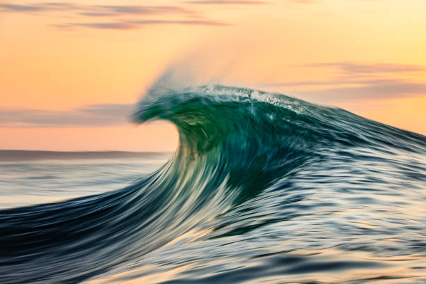 istock Smooth curved waves in the ocean with golden sky at dusk with slow shutter 1740249525