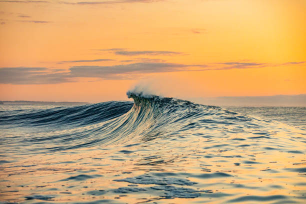 istock Smooth curved waves in the ocean with golden sky at dusk 1740249545