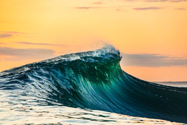 istock Smooth curved waves in the ocean with golden sky at dusk 1740249574