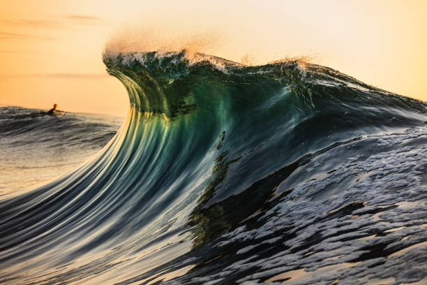istock Smooth curved wave in the ocean with golden sky at dusk 1740251106