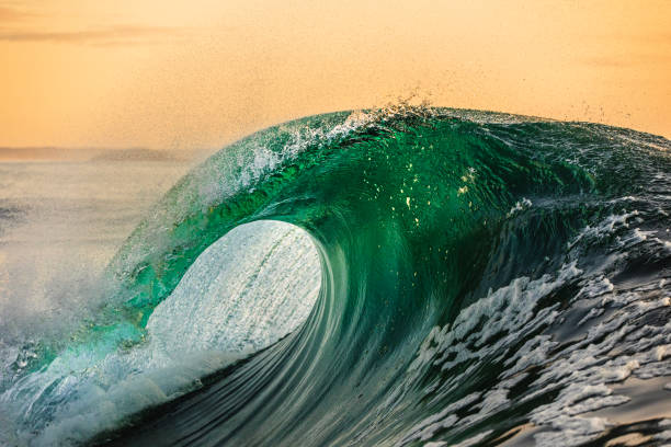 istock Powerful wave breaking in the ocean with golden sky at dusk 1740251317