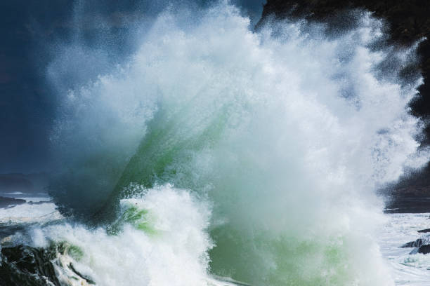 Close up of powerful backwash wave exploding from surging storm swell colliding with the coast in high contrast light. Photographed on the south coast of NSW, Australia.