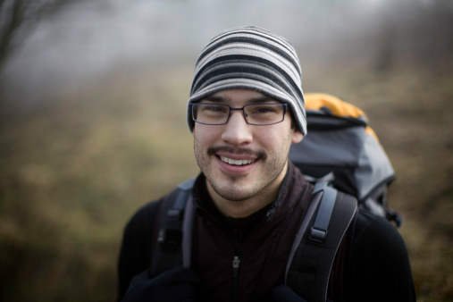 A smiling young Alaskan native on a backpacking trip.  Very shallow depth of field.  Horizontal with copy space.