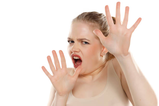 istock Scared blonde young female posing against white studio wall, keeping hands in stop gesture, trying to defend herself 1740256348