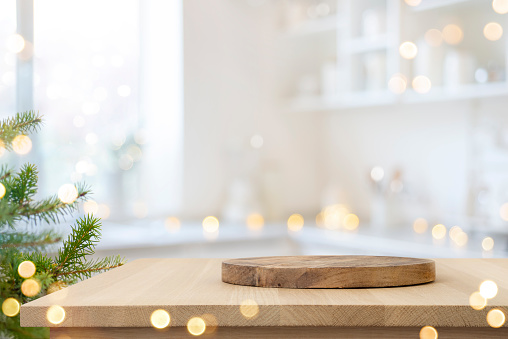 Dish serving or cutting board on wooden table in blurred kitchen with Christmas tree