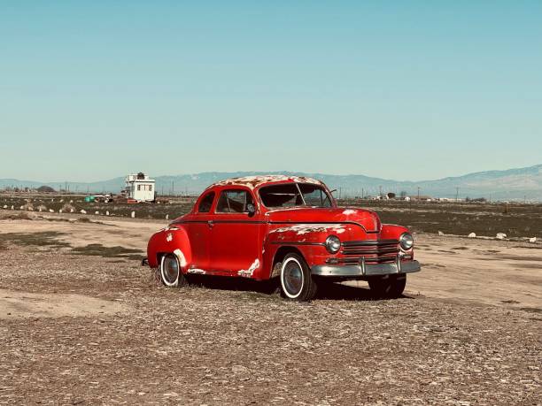 istock Vintage red car parked in a field, surrounded by tall mountains 1740273339