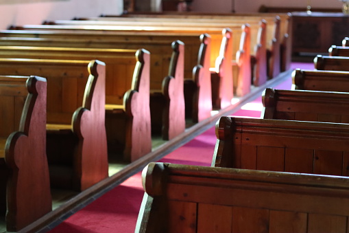 Rows of traditional church pews illuminated by sunlight