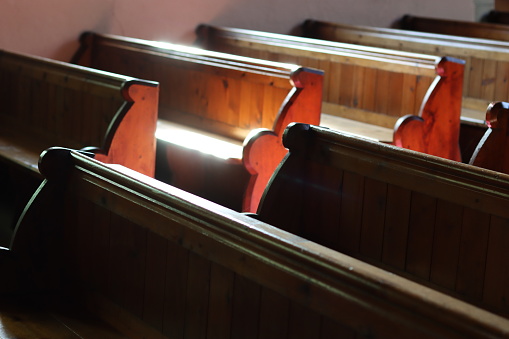 Rows of traditional church pews illuminated by sunlight
