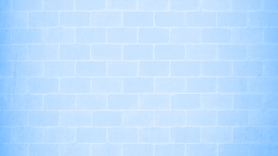 A light sky blue color brickwall made of brick tiles with slightly lighter tone of grout. Rectangle blocks on a textured horizontal vector background with no people and ample copy space and vignette.