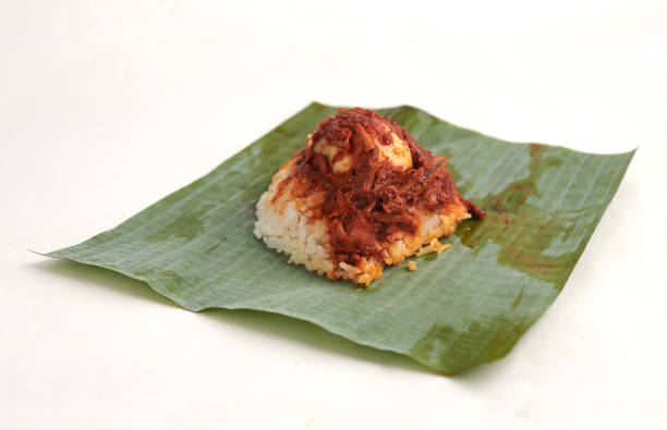 nasi lemak, a traditional malay curry paste rice dish served on a banana leaf, isolated on white background