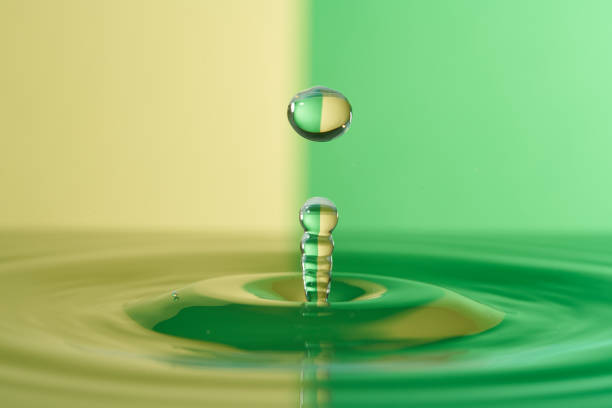 Liquid water is dropped from above into a colorful pool of water