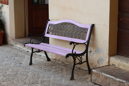 Pink wooden and metal bench outside a doorway on a back street