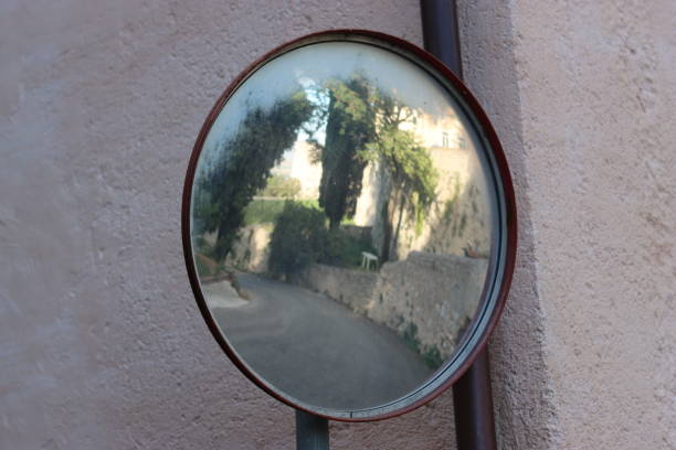 Convex blind spot mirror attached to a building wall on a sharp road bend