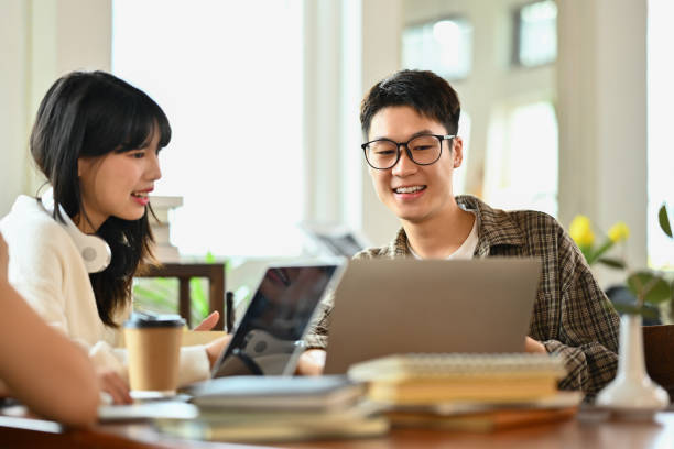 istock Friendly asian man student doing group project or preparing presentation on laptop with classmates 1740346317