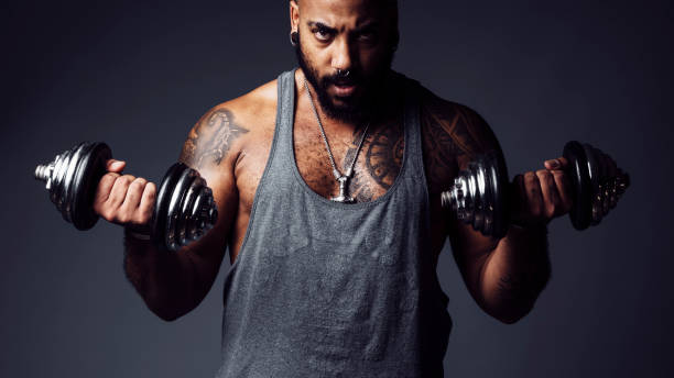 istock Black man with defiant attitude looks at camera holding two dumbbells in a studio shot 1740359766