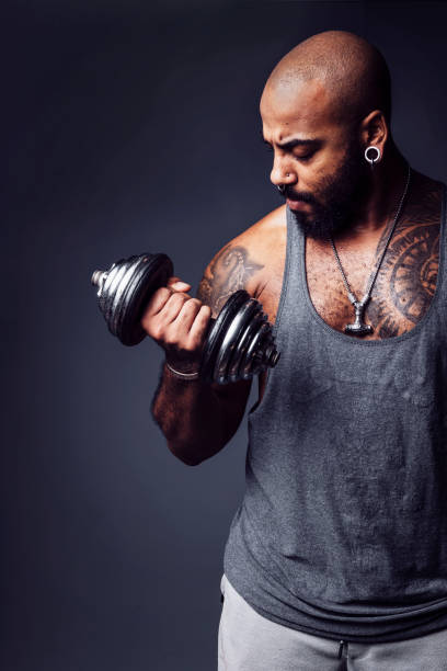 istock Mixed-race man lifting a dumbbell in a studio shot on dark gray background 1740359772