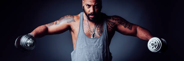 istock Muscular black man doing shoulder exercises with dumbbells in a studio shot 1740359787