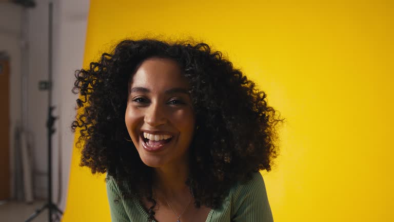 Close Up Studio Portrait Of Young Laughing Woman Standing Against Yellow Background