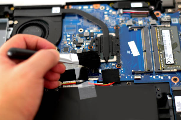istock computer technician Laptop motherboard repairman is using a converter to clean the motherboard. 1740361997