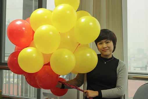The woman is very happy with a lot of ballons