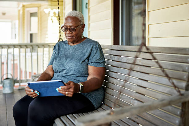 Senior Black woman on porch swing with digital tablet