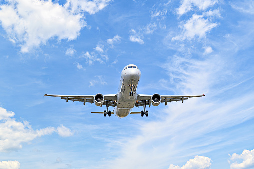 Airbus A321 passenger plane landing at the airport, under a blue sky with white clouds