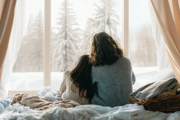 Mother and daughter enjoying winter nature in the  window stock photo