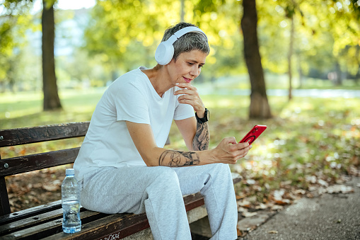 Woman in sportswear listens to music in nature
