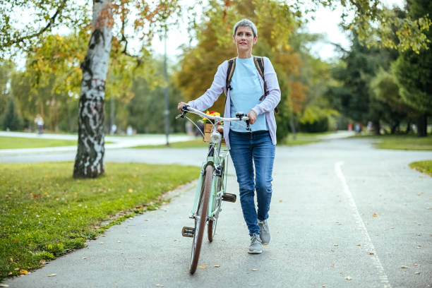 istock Woman pushes a bicycle in the park 1740417082
