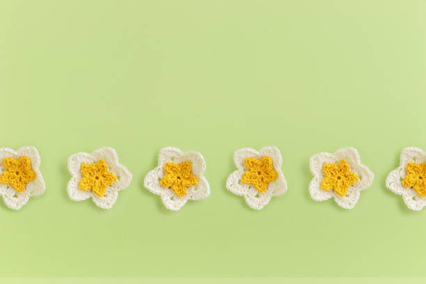 Yellow crocheted flowers row pattern on a green background