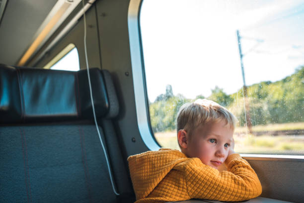 istock Young Boy with Blond Hair Gazing at Scenic Train View 1740426144
