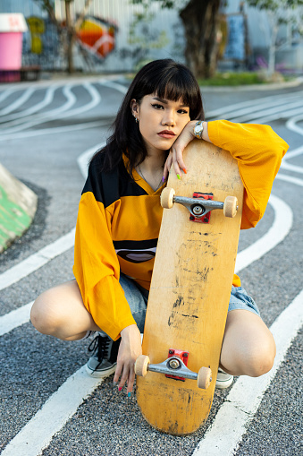 A striking stock image featuring a cool and confident young Asian girl at a skatepark, showcasing her unique style, hipster sensibility, and fashion-forward look. With an aura of confidence, she effortlessly navigates her skateboard through the urban landscape, epitomizing the skater life with flair.\n\nIn this dynamic scene, the subject's fashion-forward style and distinctive charm come to the forefront. Her skateboard serves as an extension of her personality, while her demeanor exudes an air of cool confidence. The image captures the energy and individuality of the skate culture, blending style and athleticism seamlessly.\n\nThis photograph is a fantastic representation of the fusion of fashion, hipster vibes, and skateboarding, making it an ideal choice for a wide range of creative projects that aim to capture the spirit of urban street culture and confident self-expression.