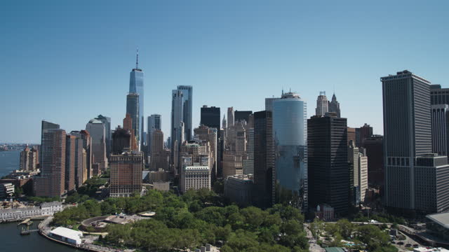 Aerial Footage of a Camera Approaching Manhattan Island with Office and Apartment Buildings. Hudson River Scenery with Yachts, Boats, One World Trade Center Skyscraper in the Middle of Skyline