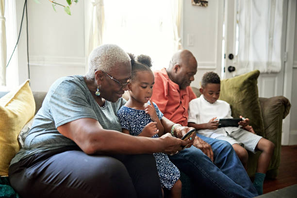 Black seniors and grandchildren using technology on weekend
