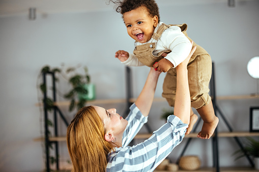 Woman is playing with a baby boy at home