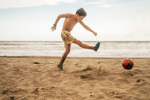 Boy playing soccer at the beach