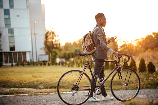 Man is pushing a bicycle and using a mobile phone