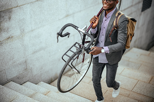 Portrait of a smiling businessman carrying his bicycle on the street.