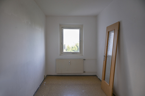Small room in need of renovation, the door leaning against the wall, concept for affordable living space out of reach in times of housing shortage, copy space, selected focus, narrow depth of field